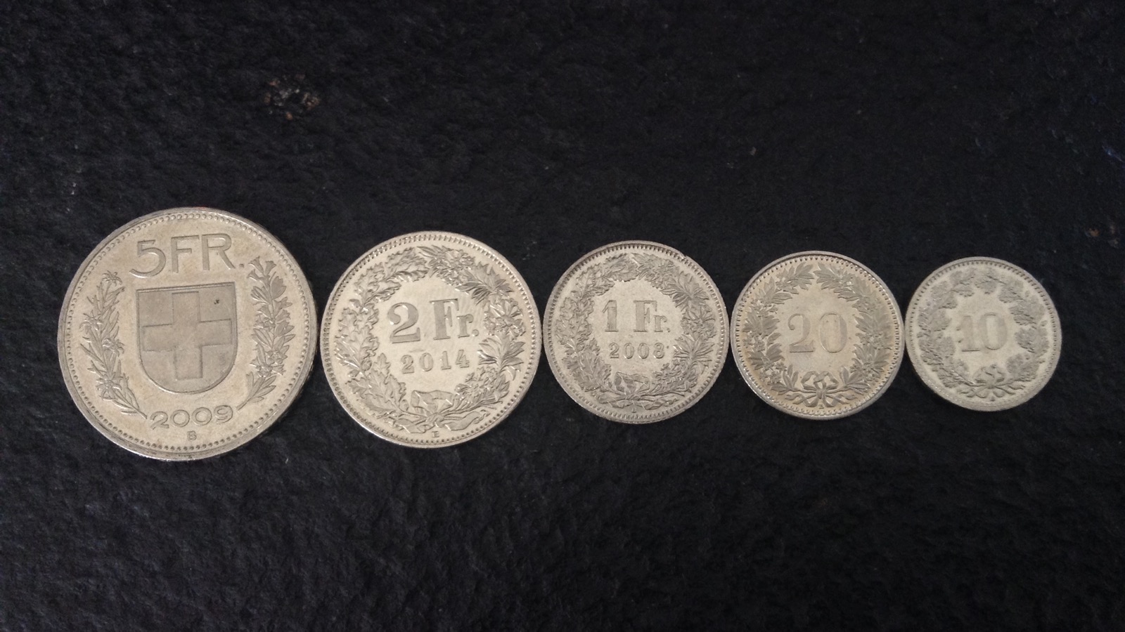 Pièces de monnaie suisses disposées sur une surface claire
